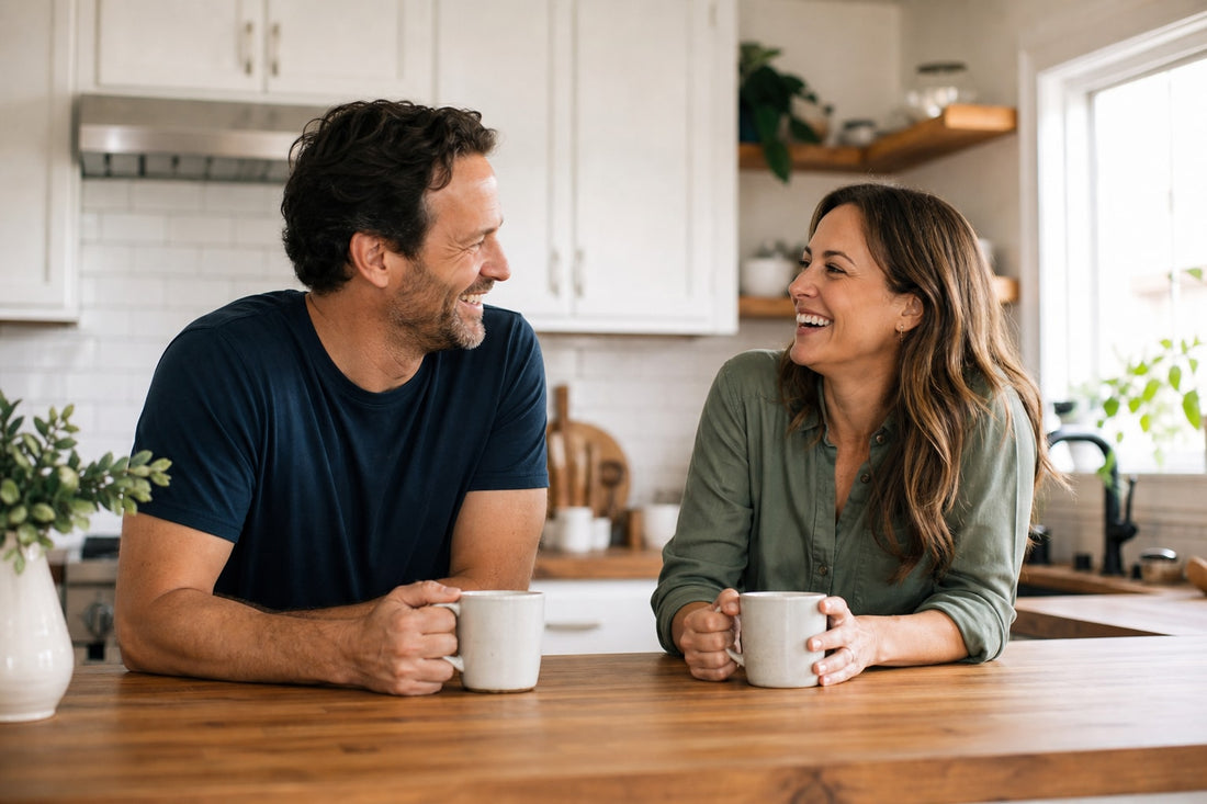 Married couple laughing together over coffee in their kitchen
