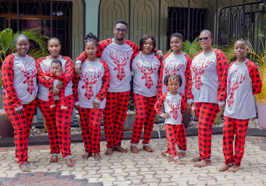 Family wearing coordinated red plaid pajama pants and gray holiday tops outdoors