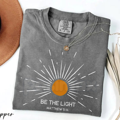 Comfort Colors® "Be The Light" Matthew 5:14 T-Shirt – Aesthetic Bible Verse Shirt, Retro Sunburst Religious Tee, Minimalist Faith-Based Sunlight Top